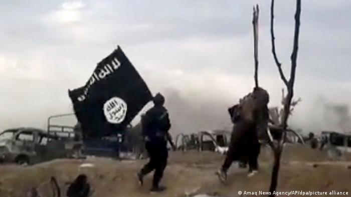 Kämpfer der Terrororganisation Islamischer Staat mit einer Flagge der Organisation