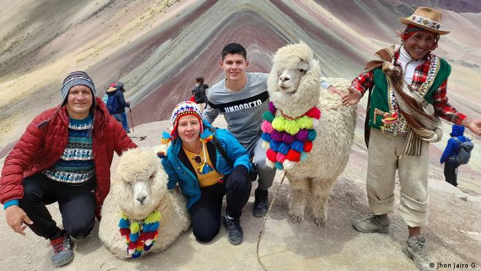 Holidaymakers posing in front of Rainbow Mountain in Peru.