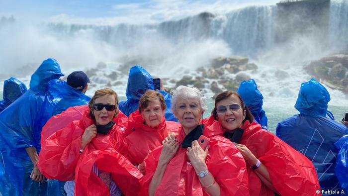 Four women in red rain capes pose in front of the Niagara Falls.