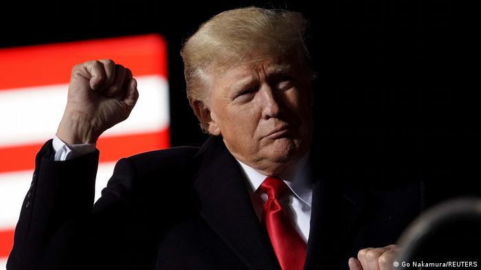 Former US President Donald Trump gestures with a fist during speech