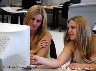 Two teenage girls in front of a computer screen