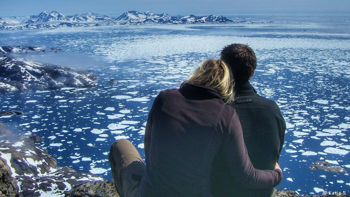 Couple in front of a sea with icebergs near Tasiilaq in West Greenland