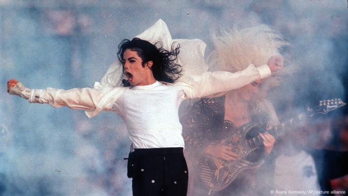 Michael Jackson on stage, arms outstretched, fluttering white shirt 