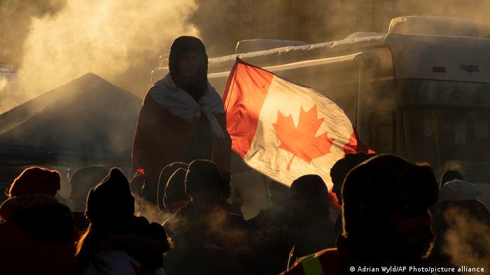 Protester standing on a barricade with a Canadian flag in background