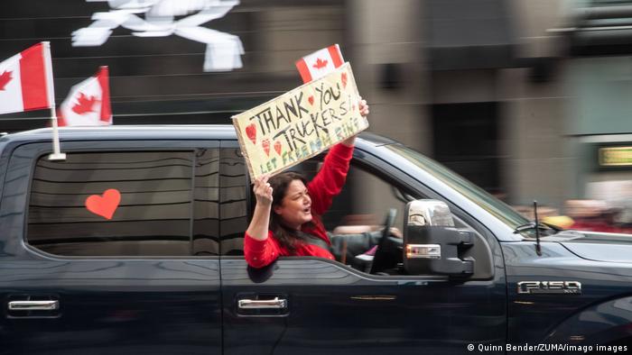 Woman holding up sign in support of the convoy from a car