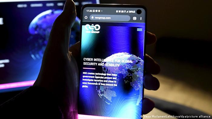 Foto simbólica de una persona que sostiene en su mano un teléfono con el logo de NSO Group en su pantalla.