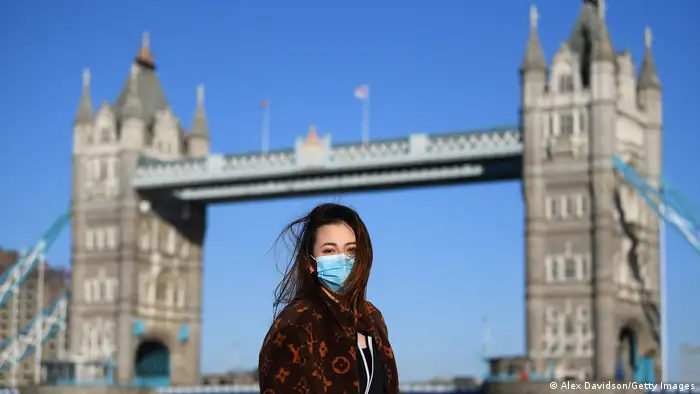  A member of the public poses for a photo in front of Tower Bridge whilst wearing a protective mask in 2020 in London