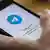 A person holds a phone with the Telegram app open