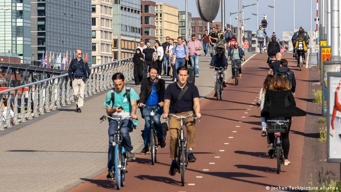 Netherlands Amsterdam.  Wide bike path and footpath with many people 
