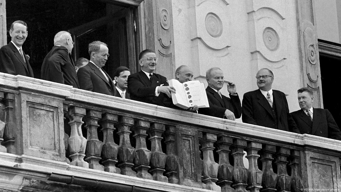 Líderes políticos em sacada exibem o Tratado de Estado de 1955, que estabelece 