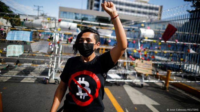 A person wearing a face mask and an anti-Bitcoin T-shirt