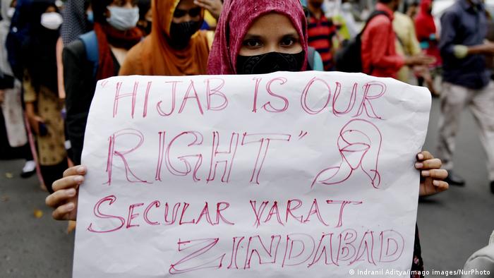 A woman wearing a hijab holds a sign