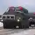 Um comboio de veículos militares de defesa aérea é utilizado em um treinamento conjunto entre Rússia e Belarus na fronteira sul dos dois países, perto da Ucrânia. Os veículos carregam equipamentos bélicos arredondados, em formato de míssil, e fazem parte do sistema de defesa antiaéreo. Os caminhões têm quatro rodas de cada lado, são da cor verde e trafegam em uma estrada de barro, cercada de neve.