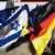 A photo of a man holding up the German and Israel flags in front of a German government plane