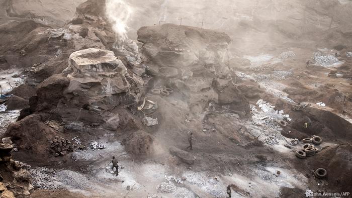 Blick in die Pissy Granite Mine: Der Boden ist mit Autoreifen und Granithaufen übersät, Staub und Rauch steigen auf.