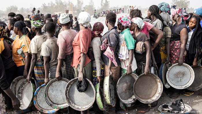 Frauen stehen dicht gedrängt in einer Schlange, in den Händen halten sie die Schalen, mit denen sie die Granitsteine aus der Mine transportieren.
