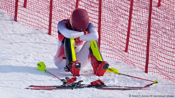 Mikaela Shiffrin hangs her head in the snow as her skis lie nearby