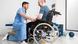 Kneeling physiotherapist before man in wheelchair Kneeling physiotherapist before man in wheelchair