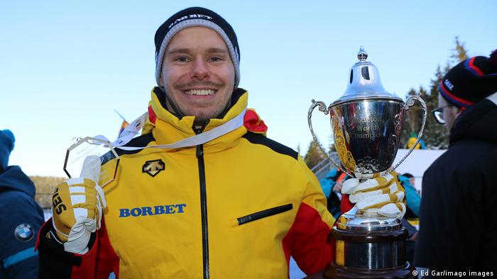 Skeleton-Weltmeister Christopher Grotheer lächelt mit Pokal in der Hand und Medaille um den Hals