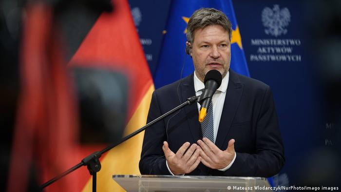 Robert Habeck speaking at a press conference in Poland in front of German and EU flags
