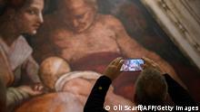 A visitor takes a photograph of a painting in the exhibition 'Michelangelo's Sistine Chapel' at Trafford Palazzo in Manchester, north-west England on February 11, 2022. - The exhibition reproduces 34 of Michelangelo's ceiling frescoes from the Vatican's Sistine Chapel which are displayed in their original size. - RESTRICTED TO EDITORIAL USE - MANDATORY MENTION OF THE ARTIST UPON PUBLICATION - TO ILLUSTRATE THE EVENT AS SPECIFIED IN THE CAPTION (Photo by OLI SCARFF / AFP) / RESTRICTED TO EDITORIAL USE - MANDATORY MENTION OF THE ARTIST UPON PUBLICATION - TO ILLUSTRATE THE EVENT AS SPECIFIED IN THE CAPTION / RESTRICTED TO EDITORIAL USE - MANDATORY MENTION OF THE ARTIST UPON PUBLICATION - TO ILLUSTRATE THE EVENT AS SPECIFIED IN THE CAPTION (Photo by OLI SCARFF/AFP via Getty Images)