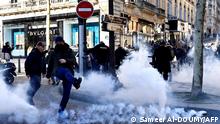 A man kicks a tear gas canister fired by French antiriot policemen on the Champs Elysees in Paris on February 12, 2022 as convoys of protesters so called Convoi de la Liberte arrived in the French capital. - Thousands of protesters in convoys, inspired by Canadian truckers paralysing border traffic with the US, were heading to Paris from across France on February 11, with some hoping to blockade the capital in opposition to Covid-19 restrictions despite police warnings to back off. The protesters include many anti-Covid vaccination activists, but also people protesting against fast-rising energy prices that they say are making it impossible for low-income families to make ends meet. (Photo by Sameer Al-DOUMY / AFP)