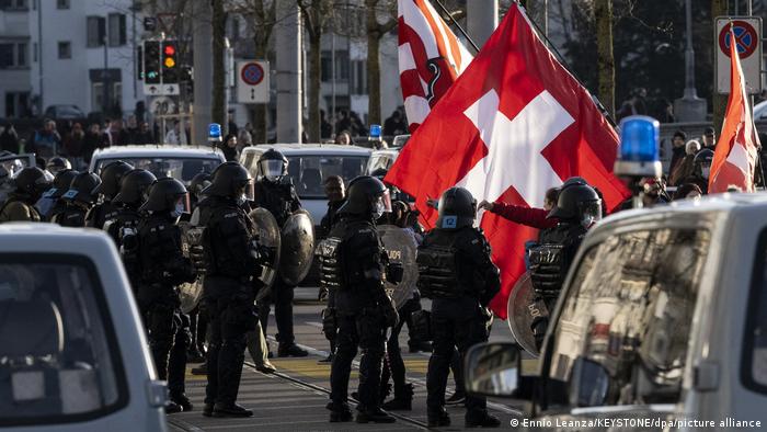 Anti-coronavirus curb protesters wave Swiss flags during an unsanctioned demonstration in Zurich