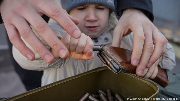 A small child struggles to remove ammunition from a clip during a basic combat training for civilians in the Donetsk region in Ukraine