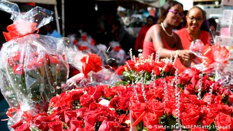 Two women looking at bouquets of roses on sale at a flower shop in Nairobi, Kenya