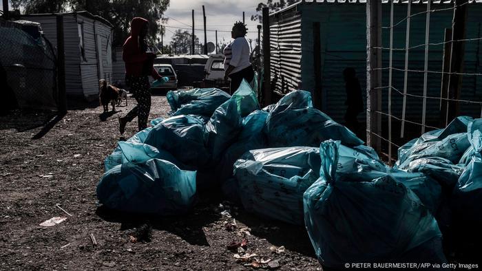 Blue rubbish bags lie abandoned in a settlement in South Africa