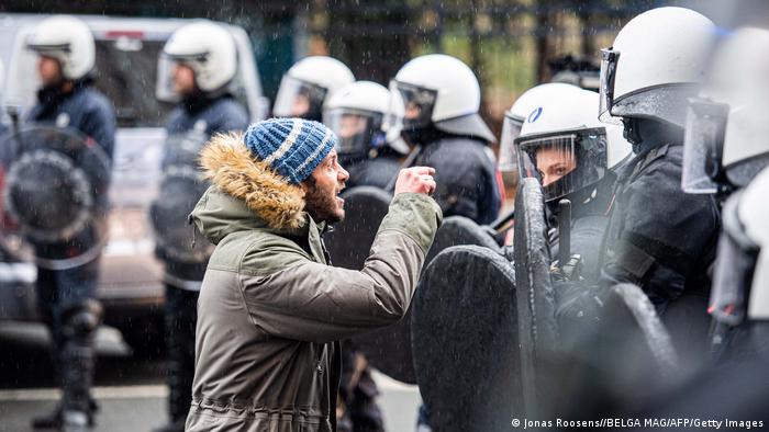 A protester gestures towards riot police in Brussels