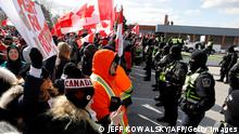 Protestors confront the Ontario Provincial Police as they try to clear the entrance to the Ambassador Bridge in Windsor, Ontario, Canada, on February 12, 2022. - Police in Canada were positioning Saturday to clear the bridge on the US border, snarled for days by truckers protesting against vaccination rules, an AFP journalist observed. We urge all demonstrators to act lawfully & peacefully, police in Windsor, Ontario, home to the Ambassador Bridge, tweeted in announcing the deployment. (Photo by JEFF KOWALSKY / AFP) (Photo by JEFF KOWALSKY/AFP via Getty Images)