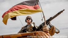 13.11.2018, Mali, Gao: Ein Soldat der Bundeswehr steht am Flughafen nahe des Stützpunkt in Gao im Norden Malis neben seinem Maschinengewehr. Die deutsche Verteidigungsministerin von der Leyen besuchte am dritten Tag ihrer Westafrika-Reise die deutschen Soldaten im Nordosten Malis. Die CDU-Politikerin besuchte das Camp Castor in Gao, wo der Großteil des deutschen Einsatzkontingents der UN-Truppe Minusma stationiert ist. Foto: Michael Kappeler/dpa