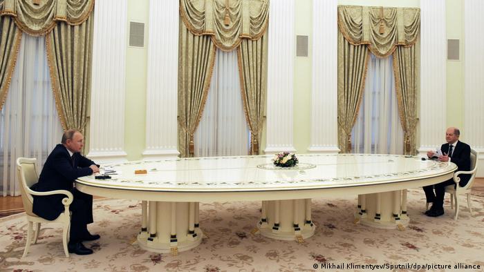 Putin and Scholz sit at a long table in Moscow