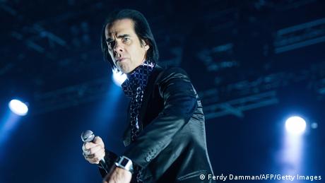 Nick Cave on stage with a microphone in his hand.
