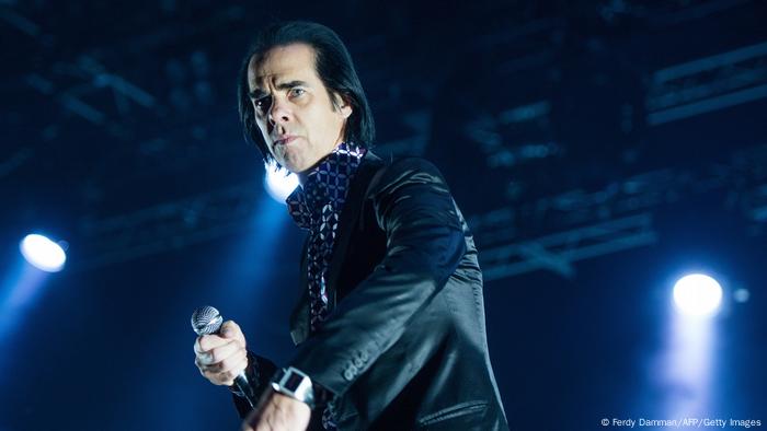 Nick Cave on stage with a microphone in his hand.