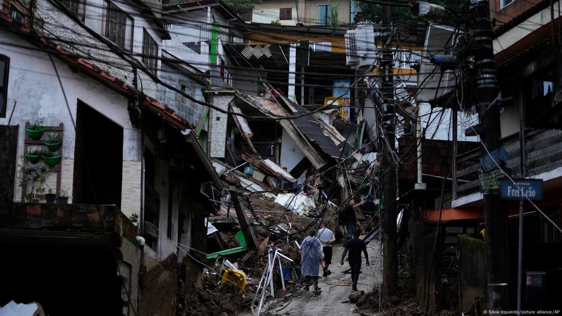 Rastro de destruição em rua de Petrópolis, Rio de Janeiro, após temporal, com casas destruídas e fios elétricos caídos