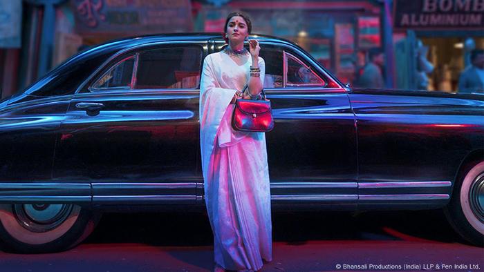 A film still from 'Gangubai Kathiawadi': A woman dressed in white in front a black car.