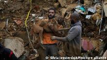 A man picks up a dog to remove from a residential area destroyed by mudslides in Petropolis, Brazil, Wednesday, Feb. 16, 2022. Extremely heavy rains set off mudslides and floods in a mountainous region of Rio de Janeiro state, killing multiple people, authorities reported. (AP Photo/Silvia Izquierdo)