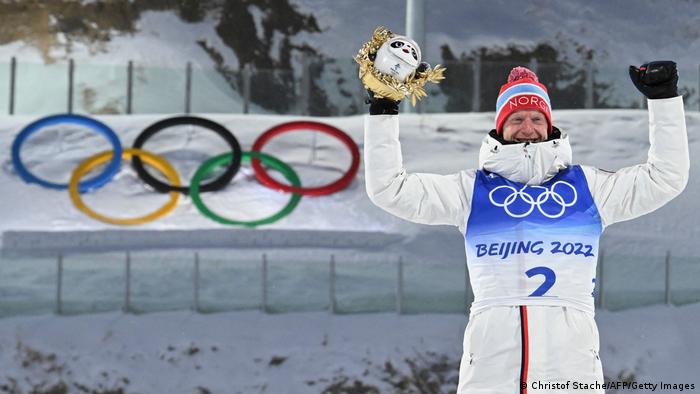 Johannes Thingnes Boe thrusts his gold medal in the air