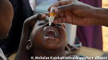 ARCHIV - 14.01.2022, Uganda, Kampala: Ein Kind erhält einen Impfstoff gegen Polio. In Afrika hat der Binnenstaat Malawi den ersten Polio-Ausbruch auf dem Kontinent seit mehreren Jahren gemeldet. (zu dpa «WHO berichtet von erstem Polio-Ausbruch seit Jahren in Afrika») Foto: Nicholas Kajoba/XinHua/dpa +++ dpa-Bildfunk +++