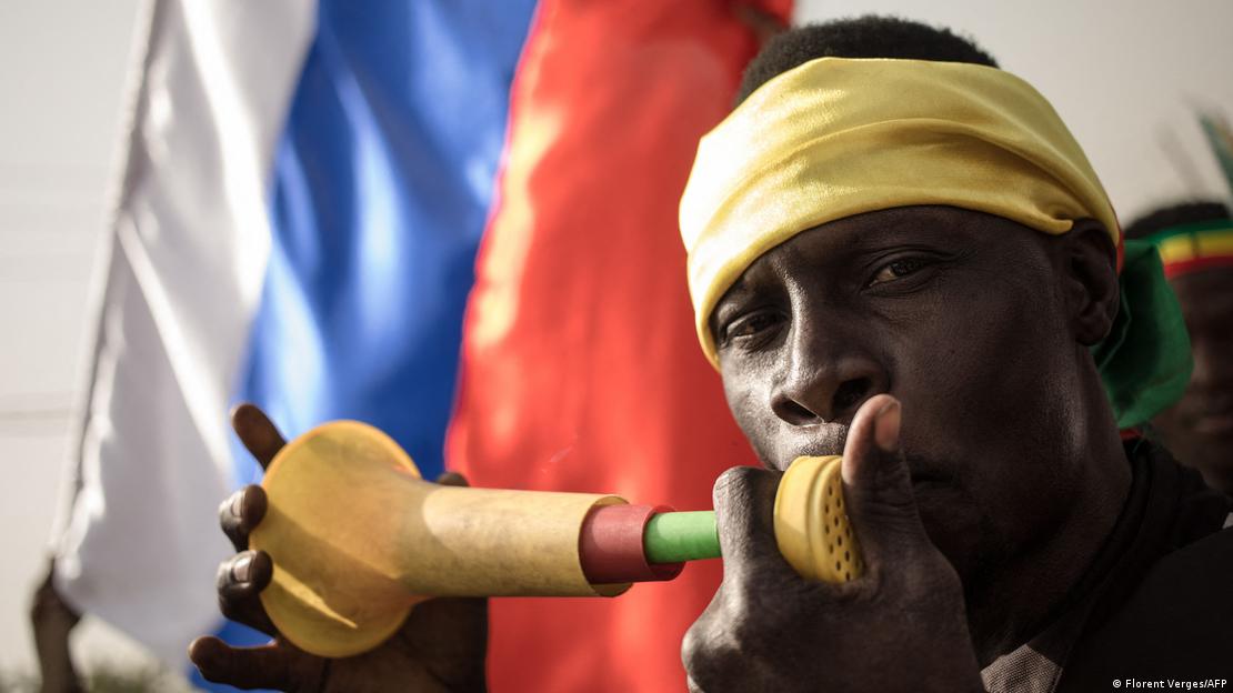 A protester blows a vuvuzela as another waves a Russian flag behind him