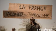 TOPSHOT - A protester holds a placard reading France, gardener of terrorism during a demonstration organised by the pan-Africanst platform Yerewolo to celebrate France's announcement to withdraw French troops from Mali, in Bamako, on February 19, 2022. - The French president announced on Febraury 16 the withdrawal of troops from Mali after a breakdown in relations with the nation's ruling military junta. France first intervened in Mali in 2013 to combat a jihadist insurgency that emerged one year prior. The French pull-out after nearly a decade is also set to see the smaller European Takuba group of special forces, created in 2020, leave Mali. (Photo by FLORENT VERGNES / AFP) (Photo by FLORENT VERGNES/AFP via Getty Images)