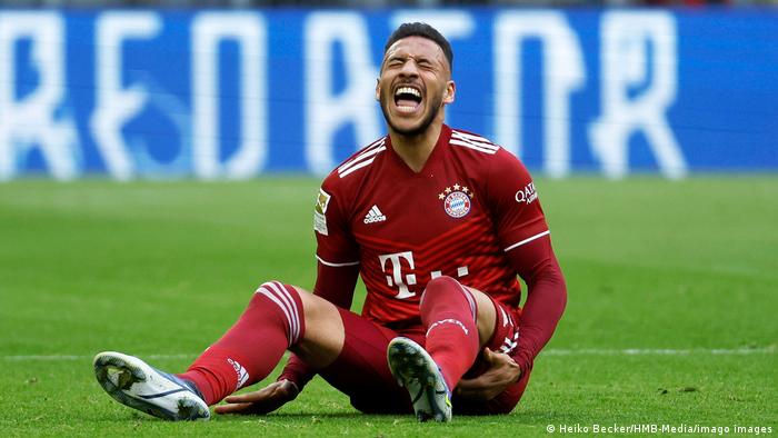 Bayern Münchens Spieler Corentin Tolisso sitzt auf dem Rasen und schreit mit verzerrtem Gesicht