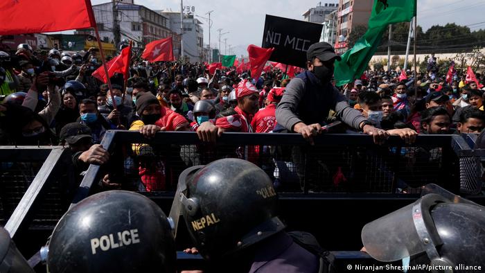 Nepalese riot police stand behind barriers separating them from protesters
