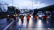 dpatopbilder - 21.02.2022, Hamburg: Klimaaktivisten der Aktion ·Aufstand der letzten Generation· blockieren am Morgen eine Kreuzung am Zollamt Waltershof zur Köhlbrandbrücke und zur Autobahn A7. Foto: Christian Charisius/dpa +++ dpa-Bildfunk +++