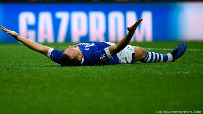 Yevhen Konoplyanka lies on the turf with his arm spread in front of a Gazprom logo on the sideline.