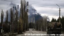 22.2.2022, Luhansk, Ukraine, A military vehicle drives on a road as smoke rises from a power plant after shelling outside the town of Schastia, near the eastern Ukraine city of Lugansk, on February 22, 2022, a day after Russia recognised east Ukraine's separatist republics and ordered the Russian army to send troops there as peacekeepers. - The recognition of Donetsk and Lugansk rebel republics effectively buries the fragile peace process regulating the conflict in eastern Ukraine, known as the Minsk accords. Russian President recognised the rebels despite the West repeatedly warning him not to and threatening Moscow with a massive sanctions response. (Photo by Aris Messinis / AFP) (Photo by ARIS MESSINIS/AFP via Getty Images)