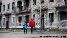 TOPSHOT - A woman with a boy walk past an old destroyed building in small town of Krasnogorivka, Donetsk region on February 22, 2022. - Russian President said on February 22, 2022 that Western-brokered peace agreements seeking to end a conflict in eastern Ukraine no longer existed. Russian President recognised the independence of the ex-Soviet country's separatist regions despite the West repeatedly warning him not to and threatening Moscow with a massive sanctions response. (Photo by Aleksey Filippov / AFP)