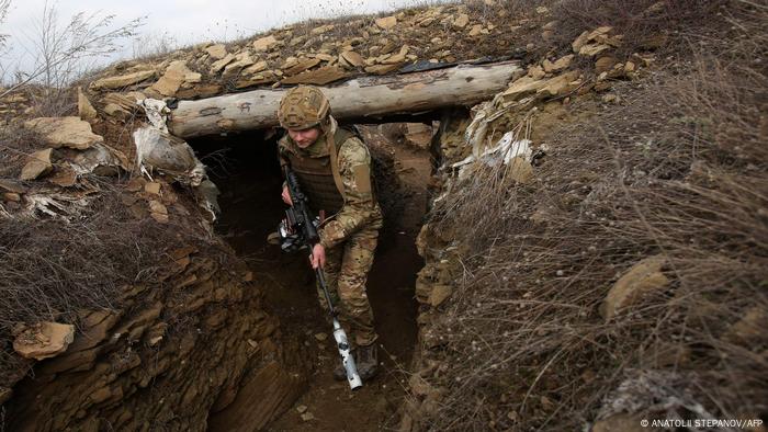 A Ukrainian serviceman walks along a trench